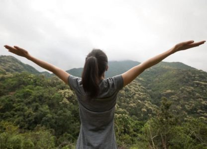Woman with arms outstretched overlooking beautiful view of mountains