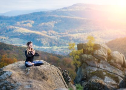 Woman in seated meditation on rock overlooking beautiful view