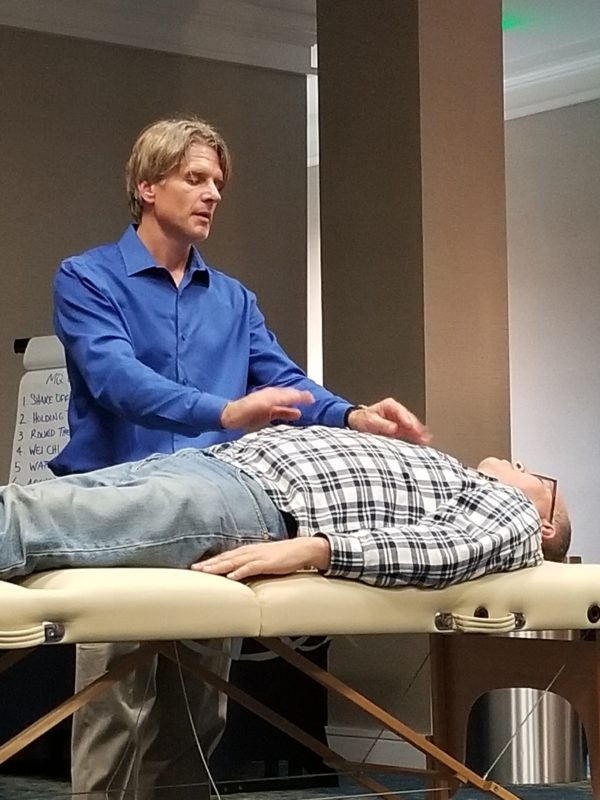 David Coon practicing Qigong on a patient laying on a table