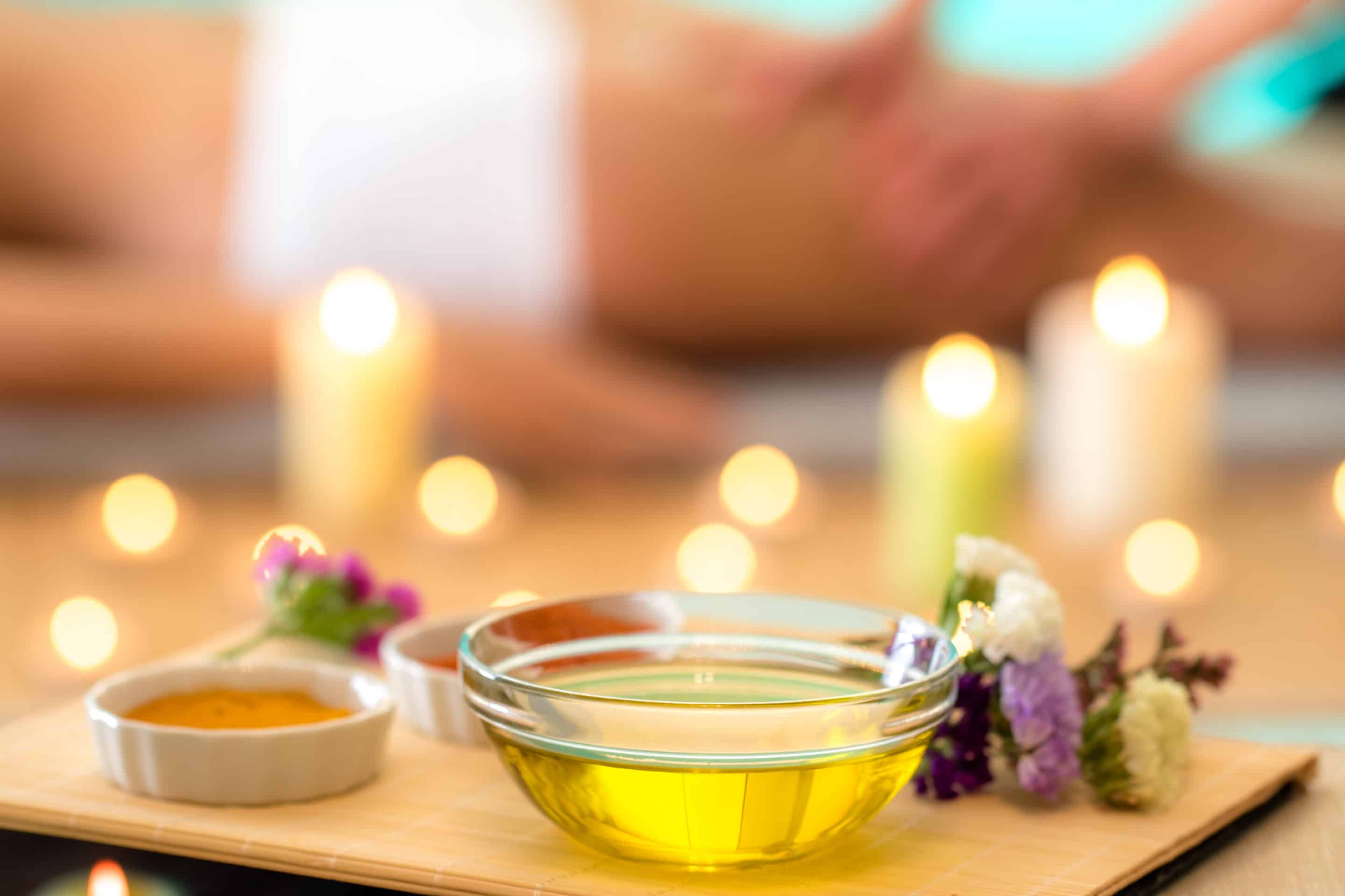 Spa oils displayed in bowls on a tray with flowers.