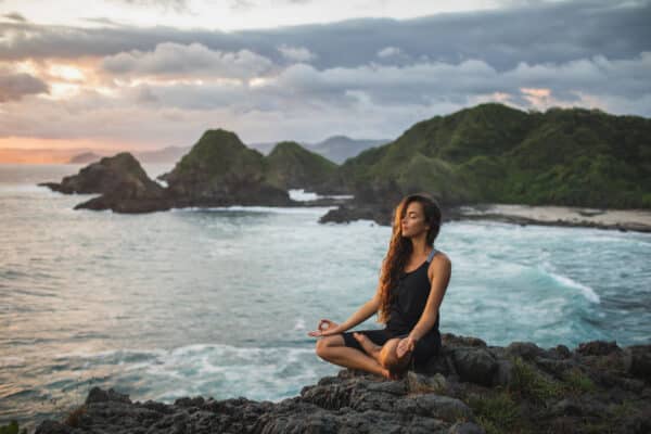Woman meditating near ocean. Qigong Awareness - Tea With The Master Full Day Event. In person and Live Streaming.