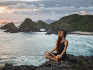 Woman meditating near ocean. Qigong Awareness - Tea With The Master Full Day Event. In person and Live Streaming.